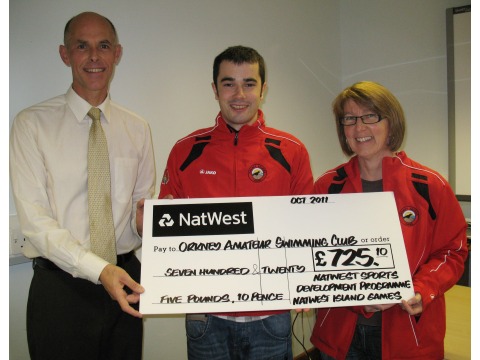 Team Manager and Secretary of Orkney Island Games Association Kieran Henderson presenting cheque to OASC President Helen Rothnie and Coach Ben Delaney